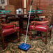 A Carlisle Duo-Sweeper on the floor of a dining room table with chairs.