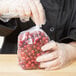 A person in a plastic glove holding a LK Packaging plastic food bag of cranberries.