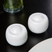 Two white 10 Strawberry Street Taverno salt and pepper shakers on a table.