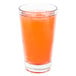 A Libbey stackable mixing glass filled with orange liquid and ice on a white background.
