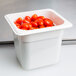 A white Cambro food pan filled with red tomatoes.