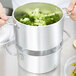 A person using a Vollrath rice and vegetable steamer to cook broccoli.