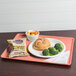 A Cambro blush dietary tray with a sandwich, broccoli, and potato chips.