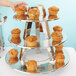 A hand reaching for a muffin on a metal display stand with other muffins.