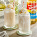 Two glasses of milkshakes with Torani Macadamia Nut flavoring, whipped cream, and straws.