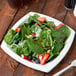 A Bare by Solo compostable sugarcane plate with a salad of strawberries, blueberries, and spinach.