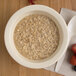 A Carlisle tan melamine nappie bowl filled with oatmeal and strawberries.