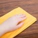 A person's hand using an orange Chicopee dusting cloth.