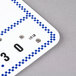 A blue and white checkered deli tag wheel with white write-on tags.