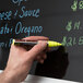 A hand writing "Chef Master" in white on a black board with a Chef Master wet erase marker.