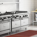 A Garland commercial stainless steel range with 4 burners and a griddle on a counter in a professional kitchen.