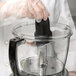 A person wearing gloves uses a Waring S blade in a food processor.