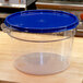A Carlisle clear plastic food storage container with a blue lid.
