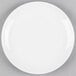 A Tuxton bright white china plate with a white rim on a gray surface.