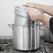 A person using a Vollrath stainless steel double boiler on a stove.