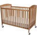 A L.A. Baby natural wood folding crib with wheels.