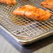Vollrath stainless steel cooling rack with salmon cooking on it.