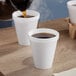 A cup of coffee being poured into a Dart white foam cup.
