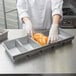 A person in gloves putting a loaf of bread into a Chicago Metallic aluminized steel bread loaf pan.
