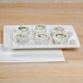 A Tuxton white rectangular china plate with sushi rolls on it.