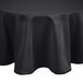 A black round Intedge tablecloth with a black hem on a table.