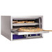 A Bakers Pride countertop pizza oven with two pizzas inside.