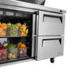 A Turbo Air refrigerated sandwich prep table with containers of fruit inside.