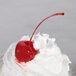A close up of a Regal Maraschino Cherry on top of whipped cream.