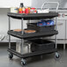 A black Metro utility cart with three deep ledge shelves holding food items.