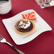 A chocolate tart with strawberries and whipped cream on a CAC Miami square porcelain plate.