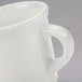 A white Tuxton coffee mug with a handle.