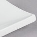 A close up of a CAC rectangular bone white porcelain platter with curved edges.