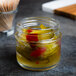 A Tablecraft glass tasting jar filled with pickled peppers on a counter.