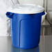A close-up of a blue Rubbermaid recycling can with a white lid.