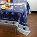 A table with a blue Penn State University table cover with food on it.