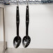 A pair of black Cambro salad bar spoons hanging from a metal rack.