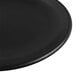 A close-up of a black Libbey Driftstone coupe plate with a round edge.