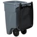 A grey plastic trash can with black wheels and a black lid.
