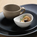 A white Libbey porcelain bouillon bowl with mushrooms and herbs.