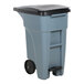 A grey Rubbermaid commercial trash can with black lid.