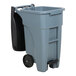 A Rubbermaid grey rectangular trash can with black wheels.