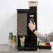 A person using a Bunn Crescendo espresso machine to make coffee.