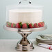 A Cal-Mil stainless steel cake stand with a cake topped with strawberries.