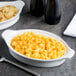 A bowl of macaroni and cheese in a white Libbey Reflections Aluma Rarebit dish with a spoon.