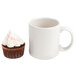 An orange striped cupcake in an Ateco baking cup next to a white mug with a handle.