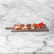 An Elite Global Solutions rectangular faux hickory wood melamine serving board with slices of watermelon and butter on it.