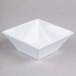 A white square Elite Global Solutions melamine bowl on a gray surface.