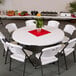 A white Lifetime round folding table with white chairs and a potted plant on it.
