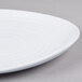A close up of a white Elite Global Solutions round melamine plate with a spiral pattern.