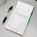 An Adams blue and white carbonless sales order book on a counter with a pen on it.